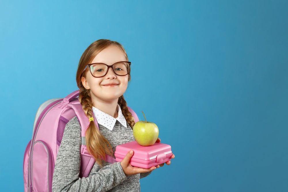 Young smiling scholar with a tupperware and an apple