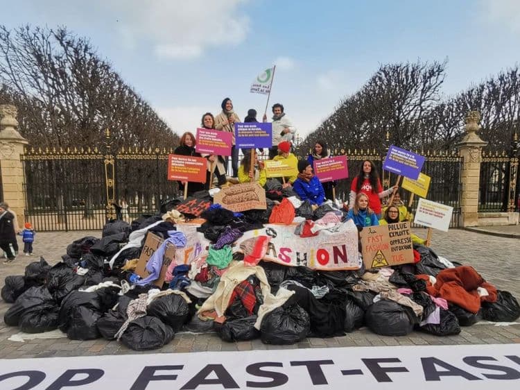 Des militants se tenant debout sur une montagne de vétement. 