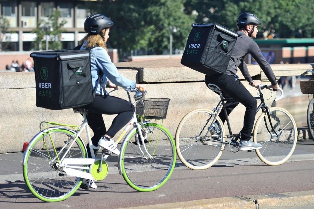 dwie osoby jadą na rowerach, mając na plecach plecaki dostawcze Ubera