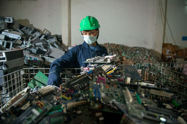Una persona que clasifica una montaña de residuos electrónicos